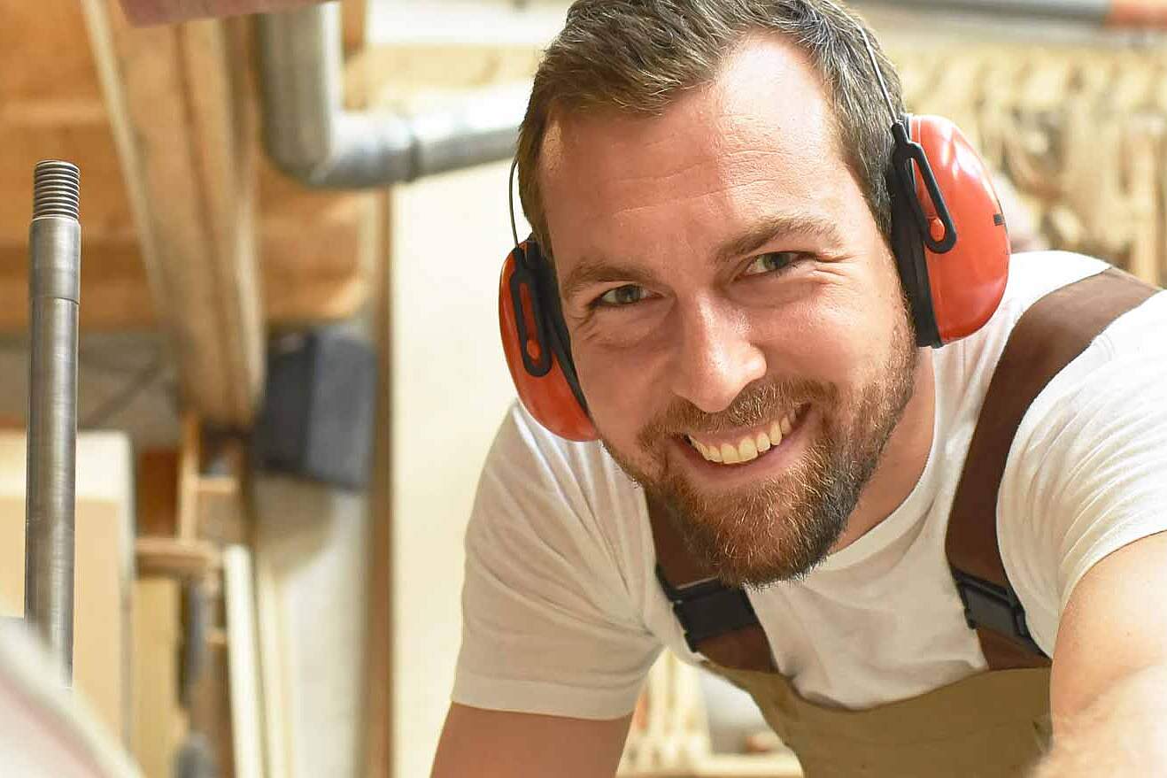 Schreiner in seiner Werkstatt mit Gehörschutz