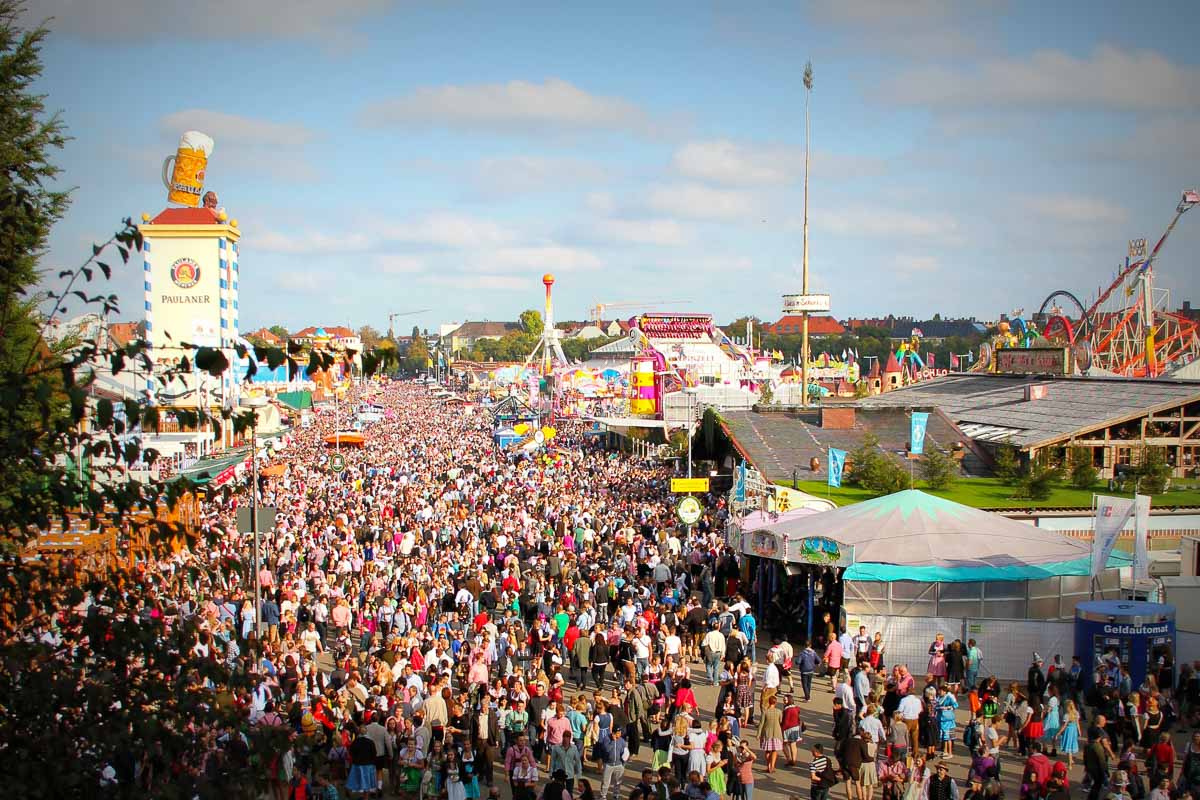 Panorama über das Münchner Oktoberfest mit vielen Besuchern, Festzelten und Fahrgeschäften