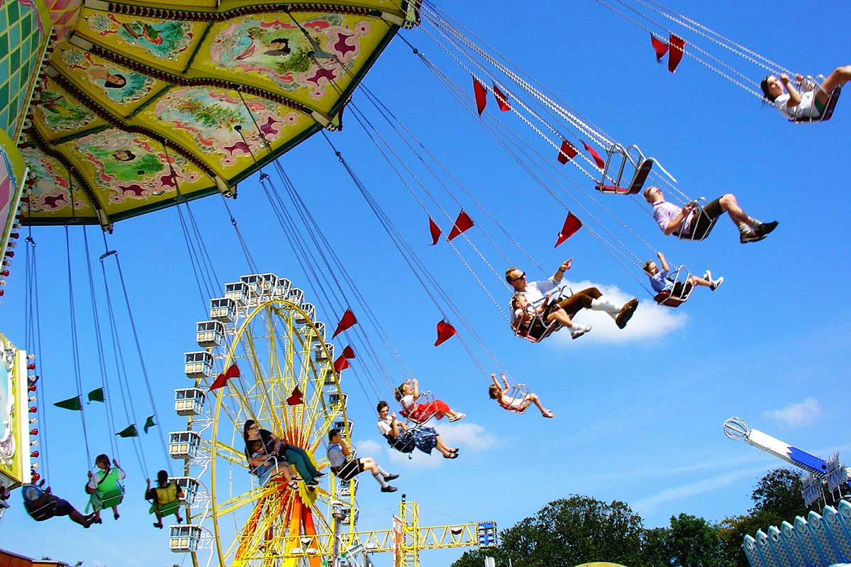 Werbeideen Frühlingsfest Kettenkarusell auf einem Volksfest, dahinter ein Riesenrad.